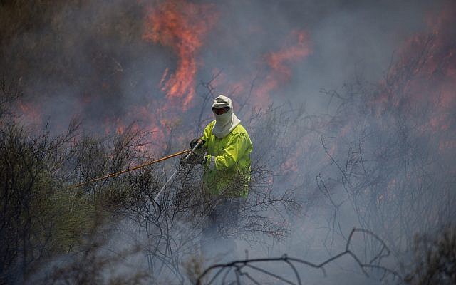 Una foto ilustrativa de un bombero que apagaba un incendio en un campo cerca de la Franja de Gaza que fue provocado por un objeto flameado que volaba desde el enclave palestino, el 5 de junio de 2018. (Yonatan Sindel / Flash90)