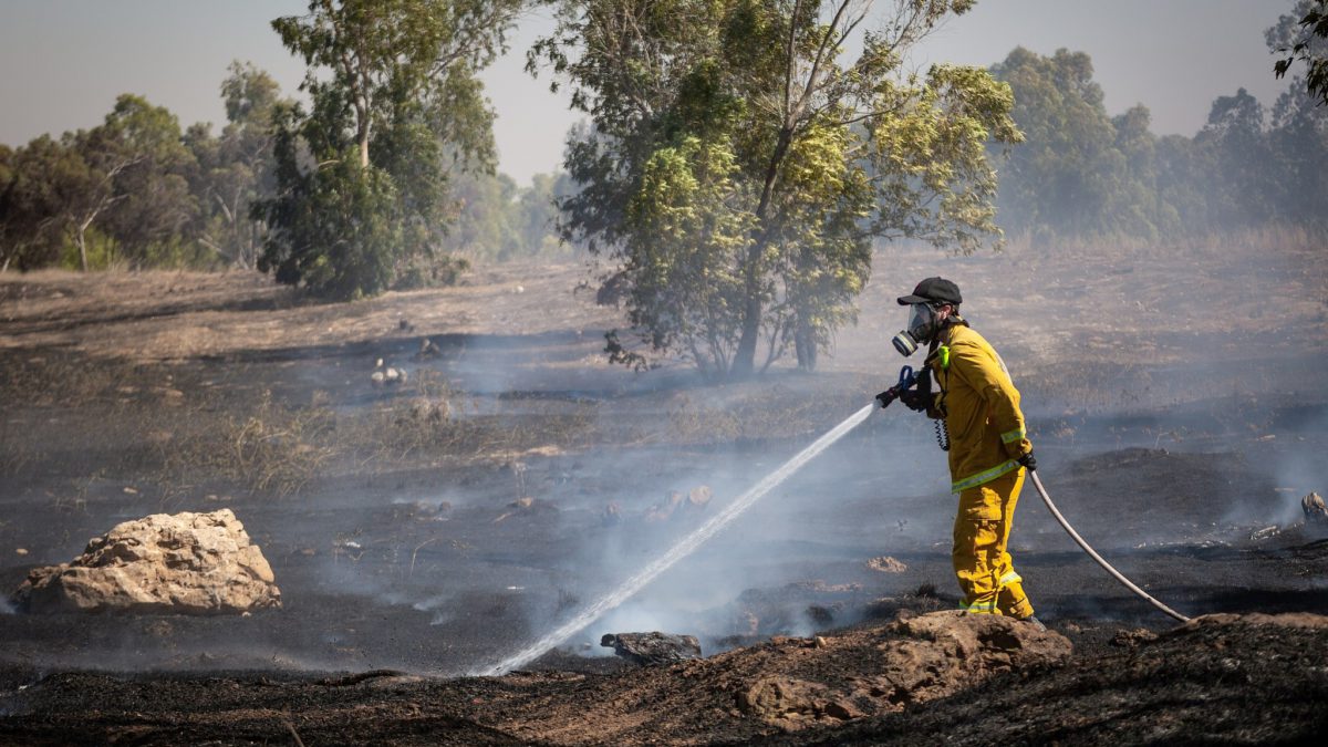 Los bomberos apagan un incendio en un campo causado por bombas incendiarias atadas a cometas voladas por los palestinos, desde la Franja de Gaza, el 27 de junio de 2018. (Flash90)