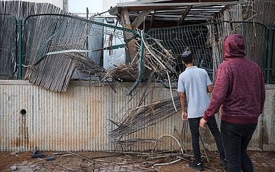 Personas en la escena donde un patio de una casa fue alcanzado por un cohete de Gaza en la ciudad de Sderot, al sur de Israel, el 14 de julio de 2018. (Hadas Parush / Flash90)