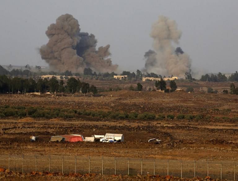 Una fotografía tomada el 24 de julio de 2018 desde la colina Tal Saki en los Altos del Golán muestra humo que se eleva sobre los edificios al otro lado de la frontera en Siria durante los ataques aéreos que respaldan una ofensiva liderada por el gobierno sirio en la provincia suroccidental de Daraa. (AFP / JALAA MAREY)