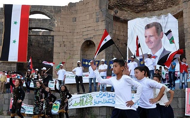 Los partidarios del presidente sirio Bashar Assad sostienen sus retratos y agitan banderas sirias durante una manifestación en apoyo de su candidatura a las elecciones presidenciales en la ciudad de Suweida, al sur de Siria, el 31 de mayo de 2014 (Foto: AP Photo / SANA)