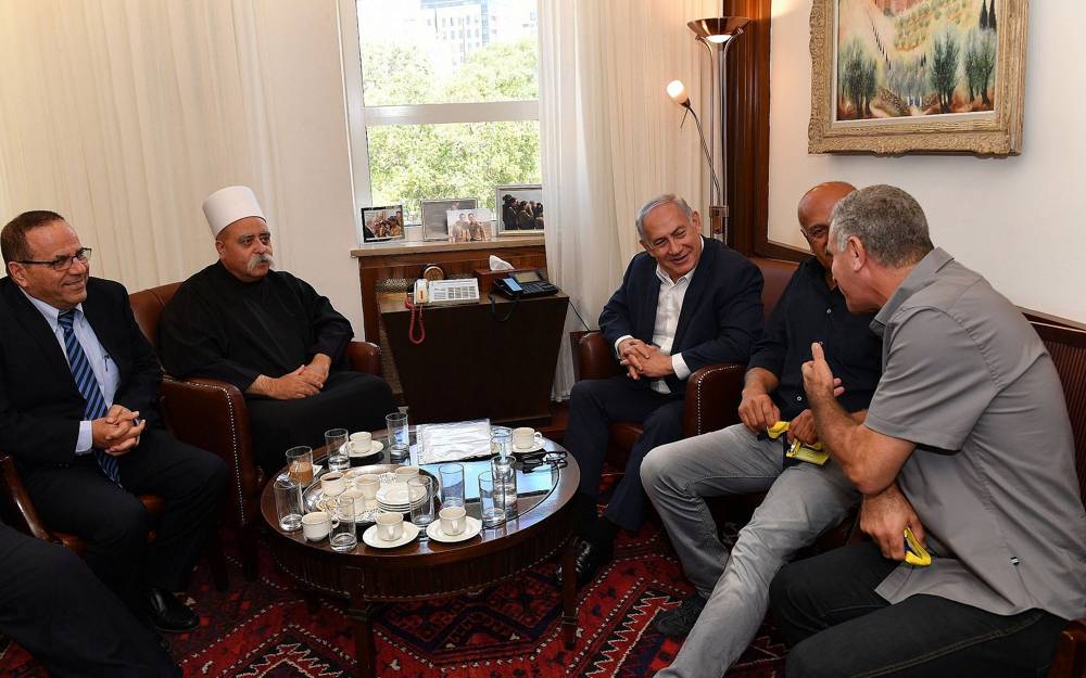 El primer ministro Benjamin Netanyahu (C) se reúne con Sheikh Muafak Tariff, líder espiritual de la comunidad drusa de Israel, el ministro de Comunicaciones Ayoub Kara (L) y otros líderes drusos en su oficina en Jerusalén para discutir la ley del Estado-Nación el 27 de julio de 2018. ( Kobi Gideon / GPO / Flash 90)