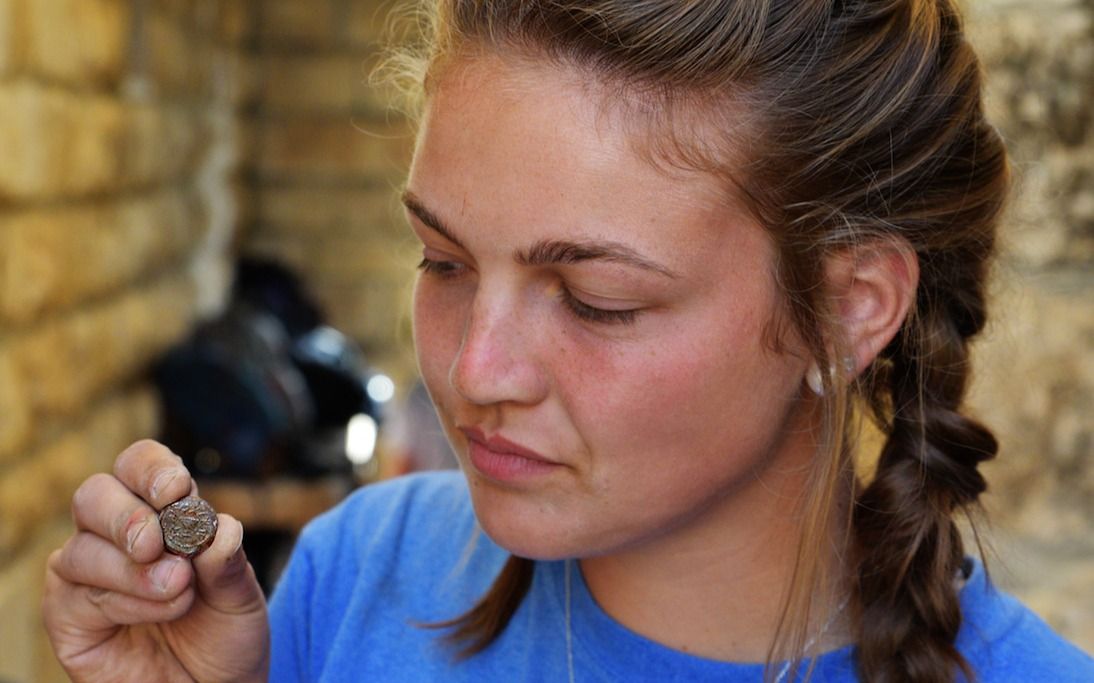 Una estudiante de Armstrong College tiene una moneda descubierta en la excavación arqueológica de Ophel fuera de las murallas de la Ciudad Vieja de Jerusalén, donde recientemente se descubrió un alijo de raras monedas de bronce de la Revuelta Judía, que data de alrededor del 66-70CE. (Eilat Mazar)