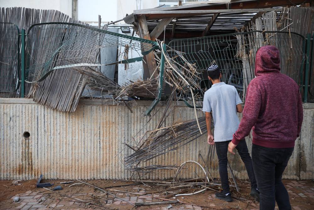 Personas en la escena en que un patio de una casa fue alcanzado por un cohete de Gaza en la ciudad de Sderot, al sur de Israel, el 14 de julio de 2018. (Hadas Parush / Flash 90)