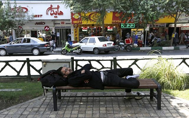 Un hombre toma una siesta en un banco en la capital iraní, Teherán, el 6 de agosto de 2018.  (AFP / ATTA KENARE)