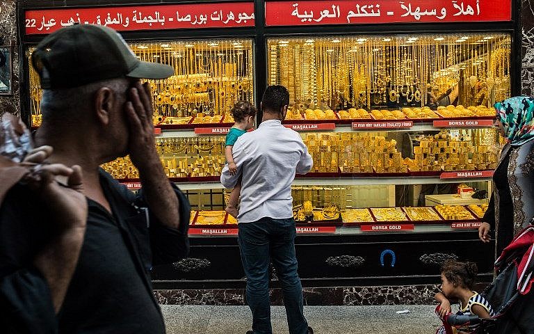 La gente pasa frente a una joyería donde se exhiben brazaletes de oro en Estambul el 8 de agosto de 2018. (AFP Photo / Yasin Akgul)