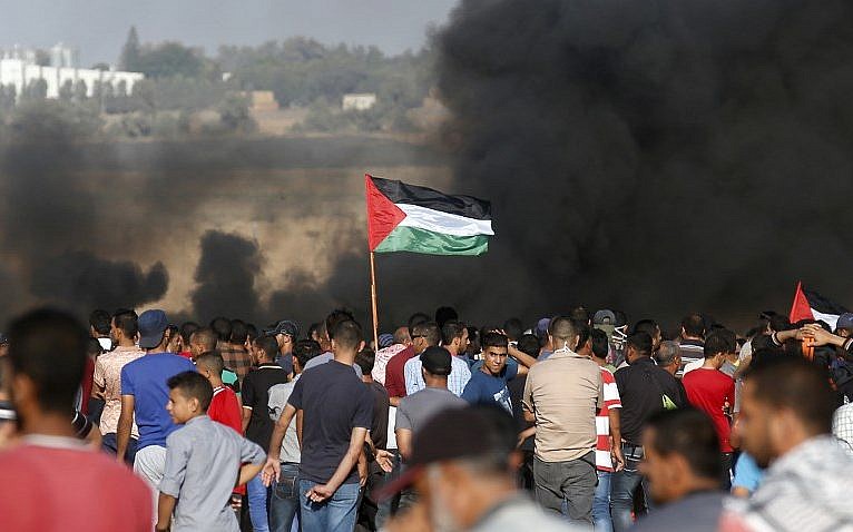 Los manifestantes palestinos agitan su bandera mientras se reúnen durante una manifestación en la frontera entre Israel y Gaza, en Khan Younis, en el sur de la Franja de Gaza, el 10 de agosto de 2018. (AFP PHOTO / Said KHATIB)