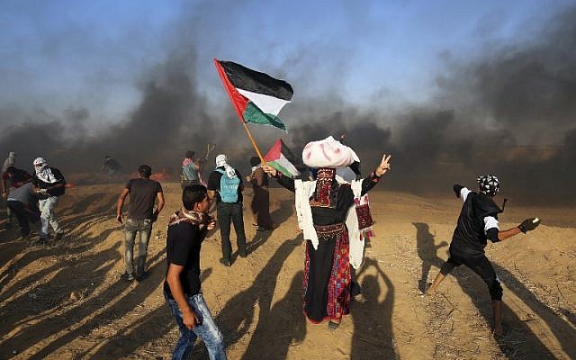 Los manifestantes palestinos arrojan piedras a las fuerzas israelíes mientras un hombre ondea la bandera nacional durante una manifestación en la frontera entre Israel y Gaza, al este de Khan Yunis en el sur de la Franja de Gaza el 24 de agosto de 2018. (AFP PHOTO / SAID KHATIB)