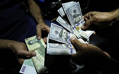 En esta foto del 8 de agosto de 2018, un hombre intercambia Riales iraníes por dólares estadounidenses en una tienda de cambio en la capital iraní, Teherán. (AFP Photo / Atta Kenare)