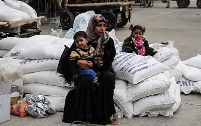 Una mujer palestina se sienta con un niño después de recibir alimentos de las oficinas de las Naciones Unidas en el campamento de refugiados de Khan Younis en el sur de la Franja de Gaza, 11 de febrero de 2018. (AFP / Said Khatib)