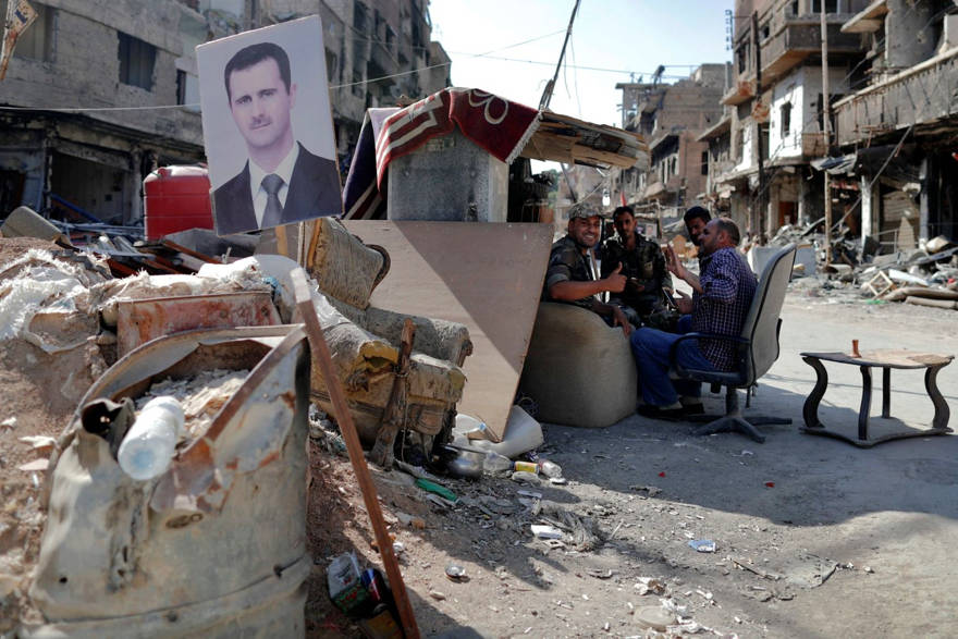 Soldados sirios portan un puesto de control con una imagen del presidente Bashar Assad en el campo de refugiados palestinos de Yarmuk, en Damasco, el 16 de julio de 2018. Hassan Ammar / AP