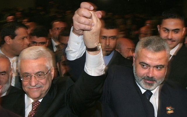 El presidente de la Autoridad Palestina Mahmoud Abbas, izquierda, y luego el primer ministro de Hamás, Ismail Haniyeh, levantan sus brazos mientras avanzan entre la multitud en una sesión especial del parlamento en la ciudad de Gaza, 17 de marzo de 2007. (AP / Hatem Moussa / Archivo )