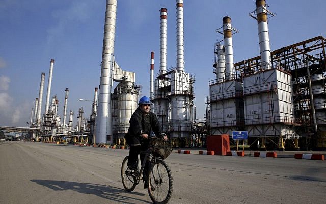 Un trabajador petrolero iraní monta su bicicleta cerca de una refinería de petróleo al sur de la capital, Teherán, 22 de diciembre de 2014. (AP / Vahid Salemi)