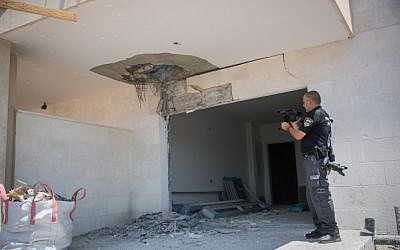 Un oficial de policía inspecciona el daño a un sitio de construcción en la ciudad de Sderot, en el sur de Israel, cerca de la frontera de Gaza después de un lanzamiento de cohete, el 9 de agosto de 2018. (Yonatan Sindel / Flash90)