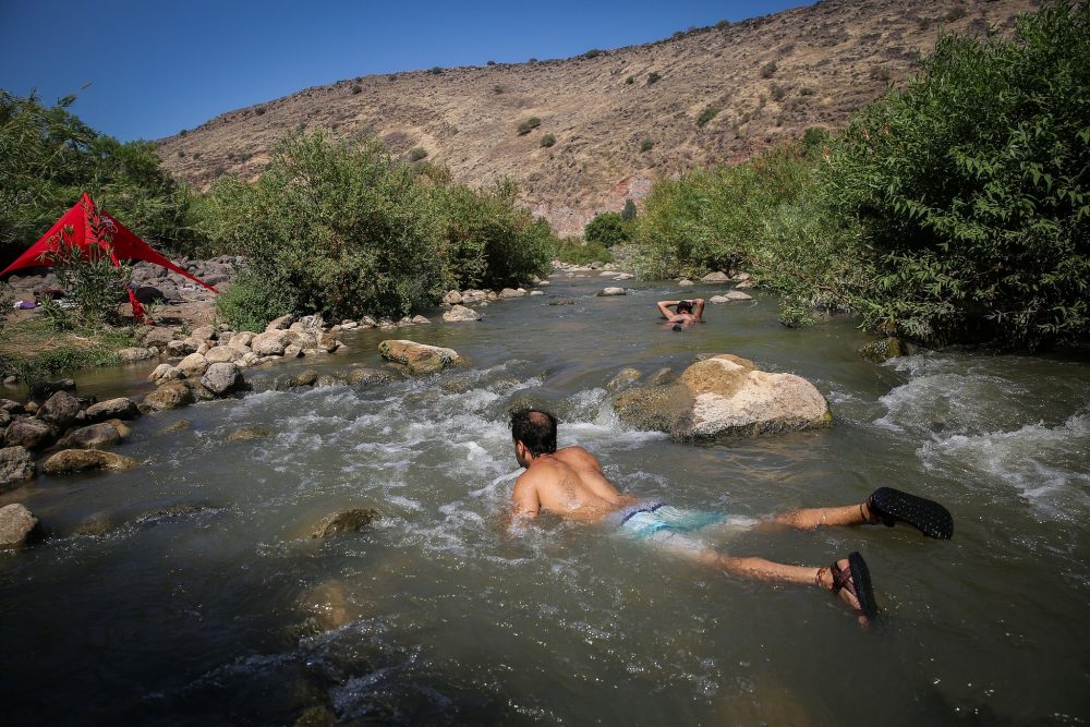 Los jóvenes israelíes se refrescan en una corriente en los Altos del Golán, en el norte de Israel. 10 de agosto de 2018. (David Cohen / Flash90)
