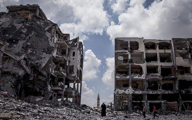 Los palestinos caminan frente a edificios destruidos por el ejército israelí en la ciudad de Beit Lahiya, al norte de la Franja de Gaza, el lunes 4 de agosto de 2014. (Emad Nasser / Flash90)