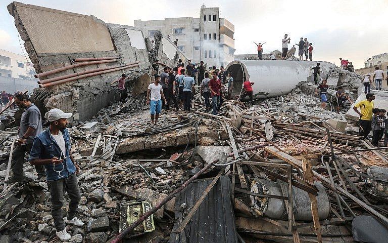 Una fotografía tomada el 9 de agosto de 2018 muestra a personas inspeccionando los escombros de un edificio atacado por la Fuerza Aérea israelí en respuesta a un ataque con cohetes que azotó el sur de Israel el 9 de agosto de 2018. (AFP Photo / Mahmud Hams)