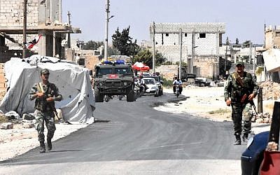 Las fuerzas sirias y rusas montan guardia mientras los civiles entran en el cruce de Abu Duhur en el extremo oriental de la provincia de Idlib, el 20 de agosto de 2018. (AFP / George Ourfalian)