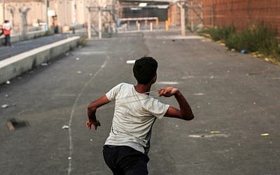 Un palestino utiliza un tirachinas para arrojar una piedra hacia las fuerzas israelíes durante los enfrentamientos en el norte de la Franja de Gaza, cerca del cruce fronterizo de Erez con Israel el 4 de septiembre de 2018. (AFP Photo / Mahmud Hams)