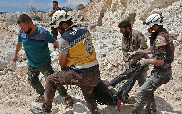 Esta fotografía tomada en Kafr Ain el 7 de septiembre de 2018 muestra a miembros de la Defensa Civil siria, también conocidos como los "Cascos Blancos", llevando a una víctima después de los ataques aéreos, a cuatro kilómetros al este de Khan Shaykhun en el campo meridional de la provincia de Idlib. (AFP / Anas Al-Dyab)