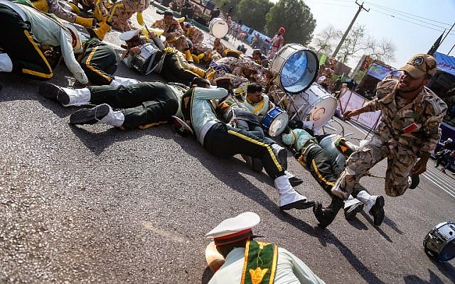 Un soldado iraní pasa corriendo junto a sus colegas heridos que yacen en el suelo en la escena de un ataque a un desfile militar en Ahvaz, el 22 de septiembre de 2018. (AFP / ISNA / MORTEZA JABERIAN)