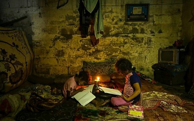 Ilustrativo: los niños palestinos hacen sus deberes a la luz de las velas durante un corte de energía en la ciudad de Gaza el 11 de septiembre de 2017. (AFP Photo / Mahmud Hams)