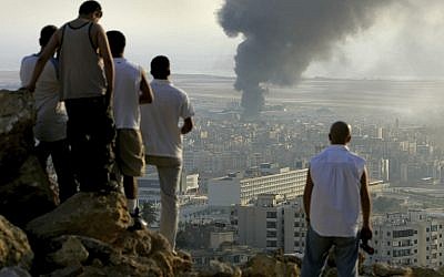 En esta foto del 14 de julio de 2006, jóvenes libaneses se reúnen en la cima de una colina con vistas a la ciudad de Beirut en el Líbano al atardecer para ver cómo el humo sigue volando desde un depósito de combustible en el Aeropuerto Internacional de Beirut, que fue golpeado por un ataque aéreo israelí. (Foto AP / Ben Curtis)