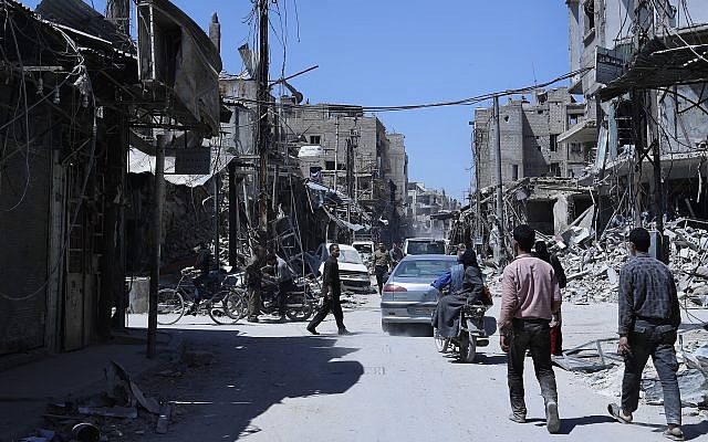 La gente camina entre edificios dañados en la ciudad de Douma, donde se sospecha un ataque con armas químicas, cerca de Damasco, Siria, el 16 de abril de 2018. (AP Photo / Hassan Ammar)