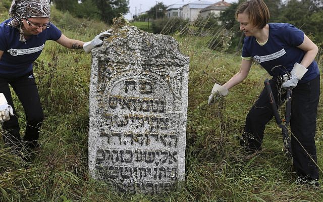 En esta foto tomada el 29 de agosto de 2018, los voluntarios limpian un antiguo cementerio judío en Rohatyn, el sitio de un proyecto de Herencia Judía, cerca de Lviv, Ucrania. (Foto AP / Yevheniy Kravs)