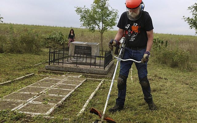 En esta foto tomada el 29 de agosto de 2018, Jay Osborn, un líder del proyecto de herencia judía de Rohatyn, limpia un antiguo cementerio judío en Rohatyn, el sitio de un proyecto de herencia judía, cerca de Lviv, Ucrania. (Foto AP / Yevheniy Kravs)