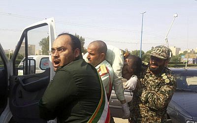 Miembros de la Guardia Revolucionaria llevan a un compañero herido después de un tiroteo durante su desfile por el 38 aniversario de la invasión de Irán en 1980, en la ciudad suroccidental de Ahvaz, Irán, 22 de septiembre. 2018. (AP Photo / ISNA, Shayan Haji Najaf)