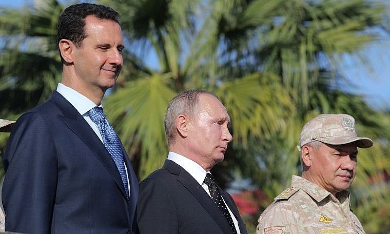 El presidente sirio Bashar al-Assad, a la izquierda, el presidente ruso Vladimir Putin y el ministro de Defensa ruso, Sergei Shoigu, inspeccionaron un desfile militar durante su visita a la base aérea rusa en Hmeimim, en la provincia de Latakia, noroeste de Siria, el 11 de diciembre de 2017. Mikhail Klimentyev / AFP)