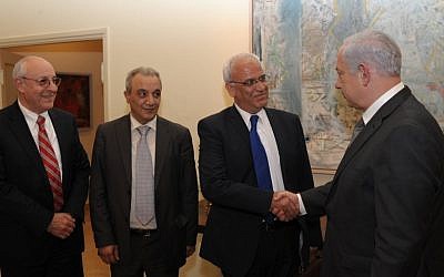 El primer ministro Benjamin Netanyahu le da la mano a Saeb Erekat en Jerusalén, abril de 2012. El ayudante de Netanyahu Yitzhak Molcho está a la izquierda y el jefe de seguridad de la Autoridad Palestina Majed Faraj está a la izquierda. (Amos Ben Gershom / GPO / Flash90)