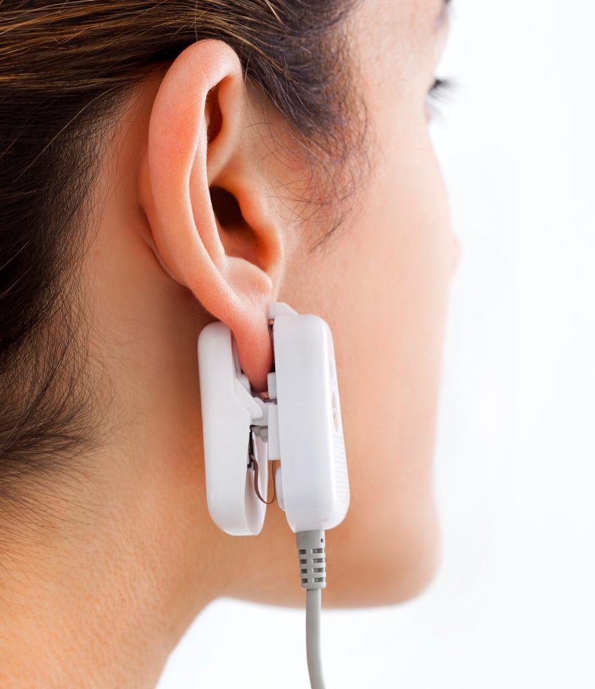 Los usuarios de GlucoTrack prueban los niveles de glucosa con un clip para la oreja conectado a una unidad de control portátil. Foto cortesía