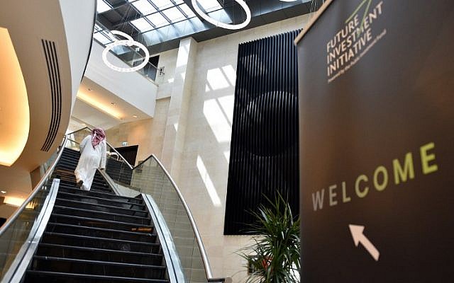 Una fotografía tomada el 22 de octubre de 2018 muestra a un hombre saudí caminando junto a un cartel de la Iniciativa de Inversión Futura FII un día antes de la conferencia que tendrá lugar en Riad del 23 al 25 de octubre (FAYEZ NURELDINE / AFP)