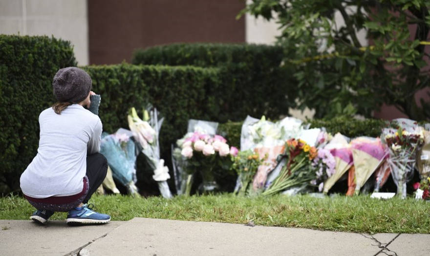 El día después de un tiroteo mortal, una mujer mira las flores como parte de un memorial fuera de la sinagoga del Árbol de la Vida, el 28 de octubre de 2018. (Brendan SMIALOWSKI / AFP)