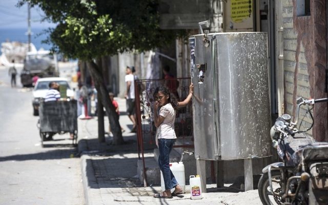 Una niña palestina llena un bidón con agua durante una ola de calor en el campamento de refugiados de al-Shati en la ciudad de Gaza el 2 de julio de 2017. (AFP Photo / Mahmud Hams)