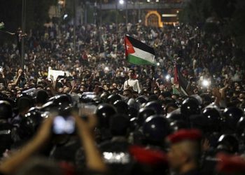 Los manifestantes jordanos gritan consignas y levantan una bandera nacional durante una manifestación frente a la oficina del Primer Ministro en la capital, Amman, a principios del 4 de junio de 2018. (Foto AP / Raad Adayleh)