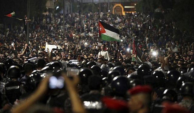 Los manifestantes jordanos gritan consignas y levantan una bandera nacional durante una manifestación frente a la oficina del Primer Ministro en la capital, Amman, a principios del 4 de junio de 2018. (Foto AP / Raad Adayleh)