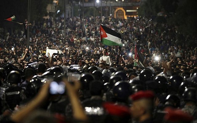 Los manifestantes jordanos gritan consignas y levantan una bandera nacional durante una manifestación frente a la oficina del Primer Ministro en la capital, Amman, a principios del 4 de junio de 2018. (Foto AP / Raad Adayleh)