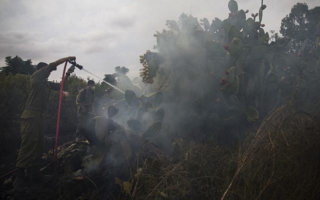 Soldados israelíes apagan un incendio iniciado por un globo con tela ardiente anexada lanzada por palestinos desde la Franja de Gaza en Moshav Kfar Maimon, 1 de octubre de 2018. (AP Photo / Tsafrir Abayov)