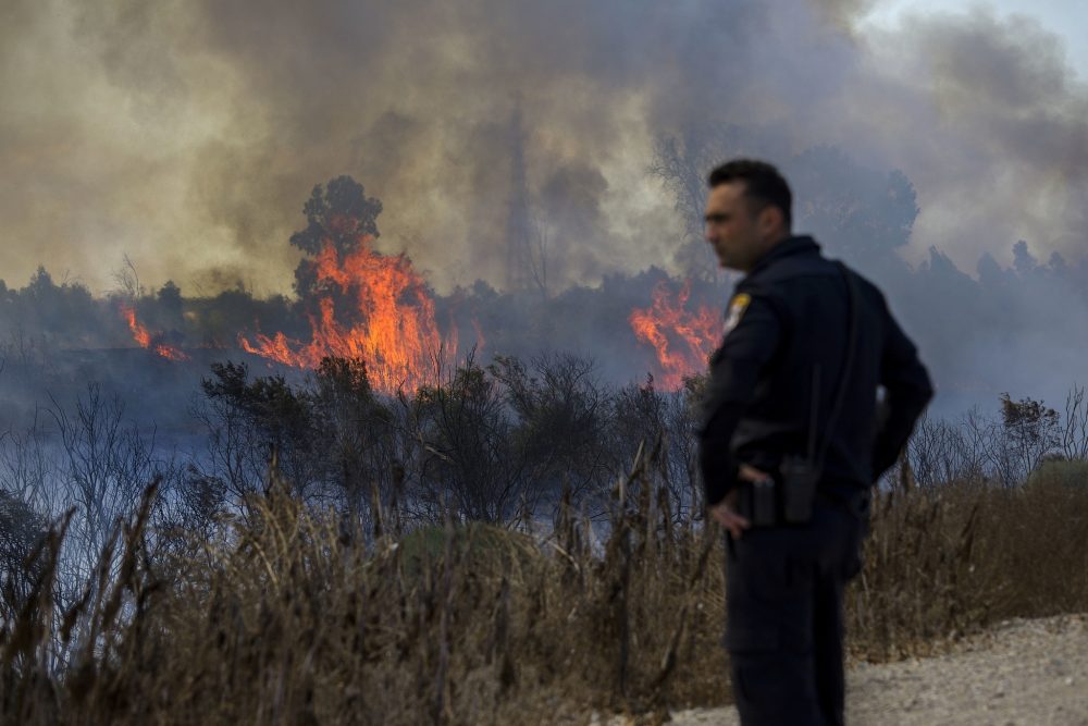 Un policía israelí observa un incendio iniciado por un globo con tela ardiente anexada lanzada por palestinos desde la Franja de Gaza en el parque natural de Karmia, cerca de Israel y la frontera de Gaza, el jueves 11 de octubre de 2018. (AP / Tsafrir Abayov)