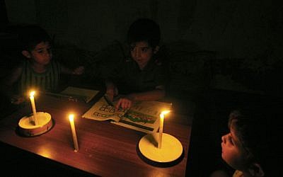 Los niños palestinos hacen su tarea a la luz de las velas en su hogar familiar, durante un corte de energía en el campamento de refugiados de Rafah en el sur de la Franja de Gaza, el 18 de septiembre de 2013. (Abed Rahim Khatib / Flash90)