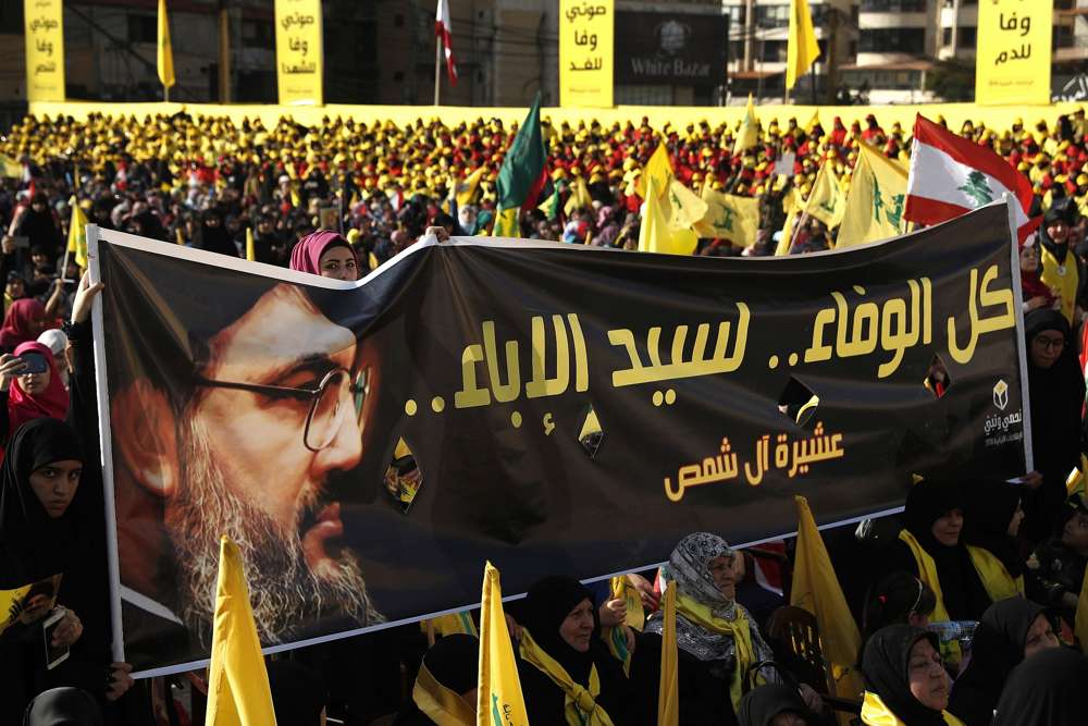 En esta foto del viernes 13 de abril de 2018, los partidarios del líder de Hezbolá, Sayyed Hassan Nasrallah, sostienen una pancarta con su retrato y palabras en árabe que dicen: “Toda la lealtad al hombre de la nobleza”. (AP / Hussein Malla)