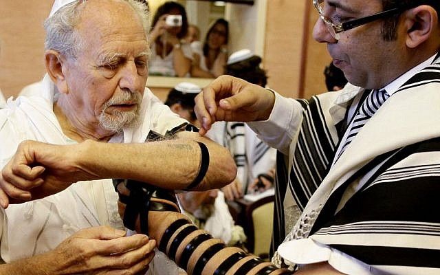 Se envuelve tefilín a un sobreviviente del Holocausto mientras celebra su bar mitzvah (crédito de foto: Flash 90)