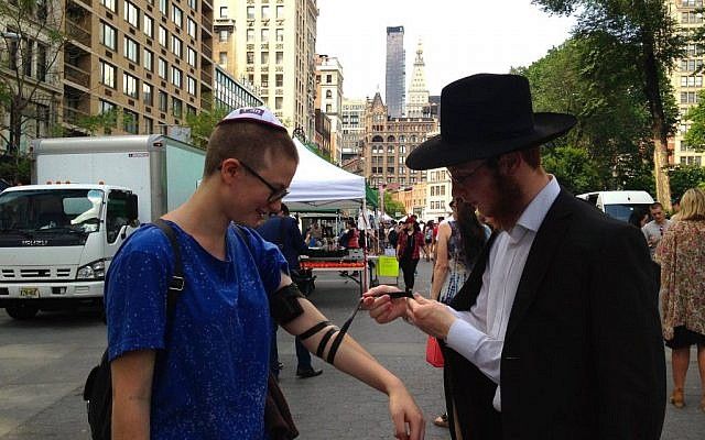 Ilustrativo: un representante de Jabad coloca filacterias en un transeúnte en Union Square de Nueva York el viernes 19 de junio de 2015 (Facebook)