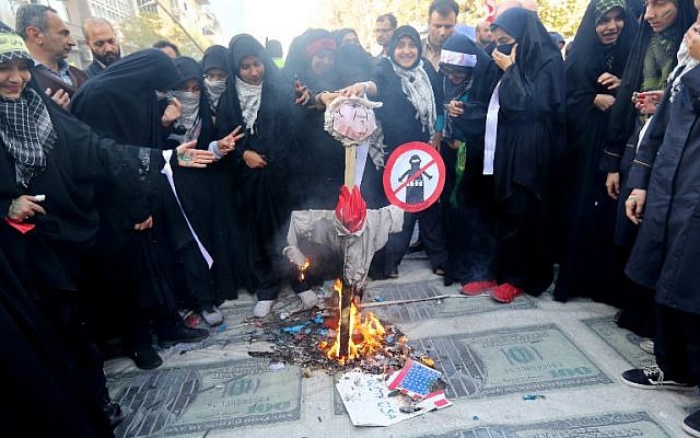 Los manifestantes iraníes queman una efigie de la red presidencial de Estados Unidos colocada en enormes impresiones de imágenes de billetes de 100 dólares estadounidenses durante una manifestación frente a la antigua embajada de Estados Unidos en la capital, Teherán, el 4 de noviembre de 2018, para conmemorar el aniversario de su asalto por parte de los manifestantes estudiantiles que provocaron Crisis de rehenes en 1979. (ATTA KENARE / AFP)