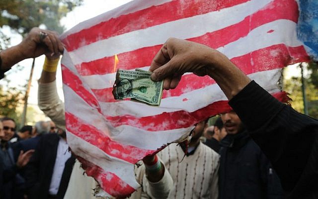 En vísperas de las nuevas sanciones por parte de Washington, los manifestantes iraníes queman un billete de un dólar y una bandera improvisada de Estados Unidos durante una manifestación frente a la antigua Embajada de los Estados Unidos en la capital iraní de Teherán el 4 de noviembre de 2018, que marca el aniversario de su asalto por parte de estudiantes manifestantes que activaron Una crisis de rehenes en 1979. (ATTA KENARE / AFP)