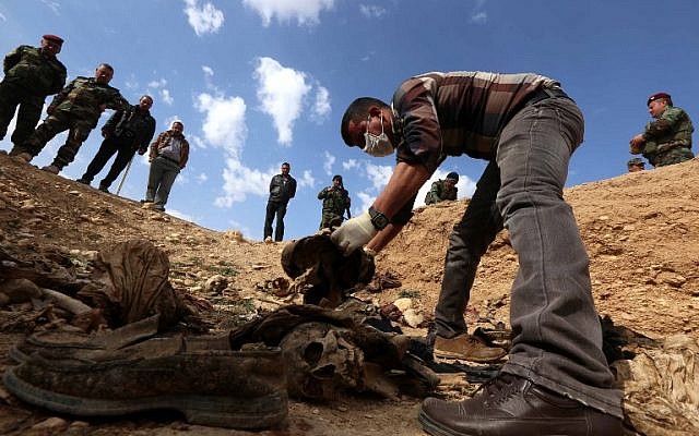 En esta foto de archivo tomada el 3 de febrero de 2015, Yazidis busca a familiares desaparecidos en los restos de personas asesinadas por jihadistas del Estado Islámico cerca de la aldea iraquí de Sinuni. (Safin HAMED / AFP)