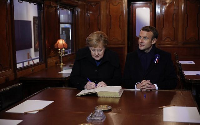 El presidente francés, Emmanuel Macron, y la canciller alemana, Angela Merkel, firman el Libro de Oro el 10 de noviembre de 2018, mientras se sientan en el vagón del tren donde se firmó el armisticio que terminó la Guerra Mundial en el desmonte de Rethondes (el Claro del Armisticio) en Compiegne, norte Francia. (Philippe Wojazer / Pool / AFP)